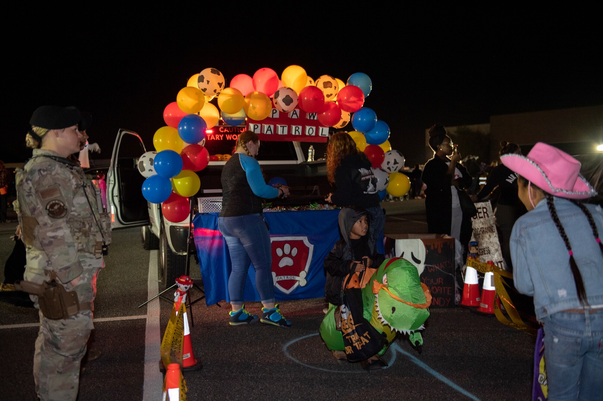 A photo of a truck decorated with blue, red, yellow, and Dalmatian print balloons with adults and children standing around.