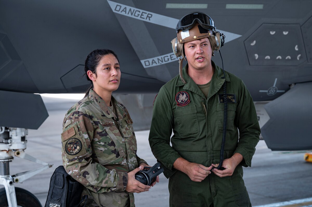 Staff Sgt. Keyli Pillaro-Estrada, 57 Aircraft Maintenance Squadron crew chief, talks with Marine Cpl. Jesse Mattics assigned to Marine Operational Test & Evaluation Squadron 1, Marine Corps Air Station Yuma, Arizona prior to a mission for Black Flag 22-2 at Nellis Air Force Base, Nevada, Sept 21. 2022.. Members of the Air Force, Navy and Marine Corps participated in consolidated F-35 Cross service maintenance and logistics training during Black Flag 22-2.  (U.S. Air Force photo by William R. Lewis)