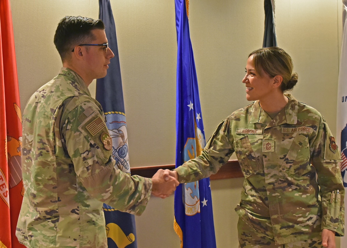 U.S. Air Force Tech. Sgt. Tech Sgt. Phillip Whitley, 315th Training Squadron geospatial-intelligence instructor, shakes hands with Chief Master Sgt. Rebecca Arbona, 17th Training Wing command chief, at Goodfellow Air Force Base, Texas, Oct. 18, 2022. As part of a longstanding military tradition, Arbona coined Whitley for his outstanding work as the NCOIC of academics and fulfilling the role as the unit fitness program manager. (U.S. Air Force photo by Airman 1st Class Zachary Heimbuch)