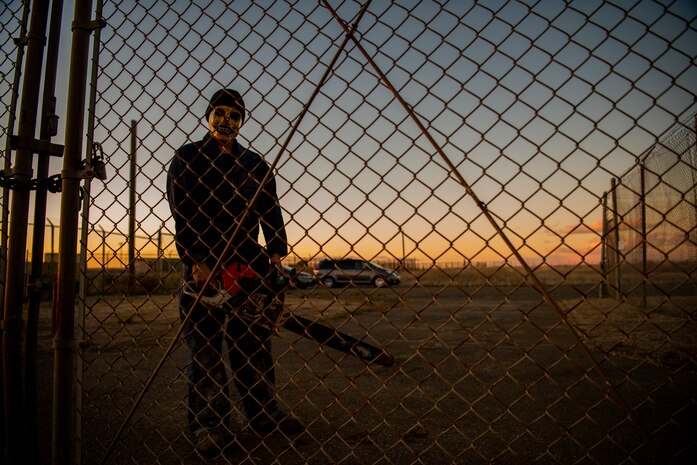 Beale volunteer Airman guards an exit with a chainsaw outside the gates at the prison at the haunted house at Beale Air Force Base