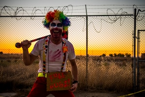 Beale volunteer Airman smiles while holding a sign at the haunted house