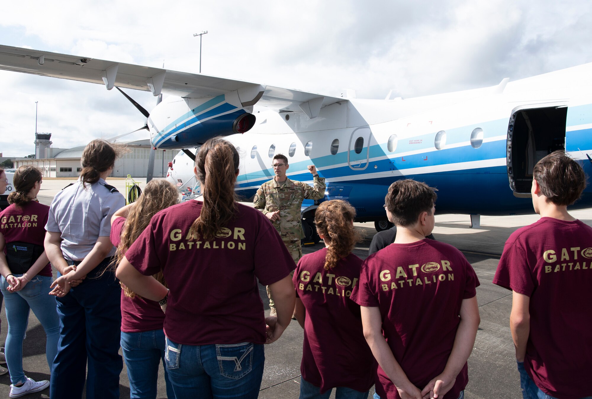 Cadets listen to a loadmaster as they stand in front of a C-146A Wolfhound aircraft.