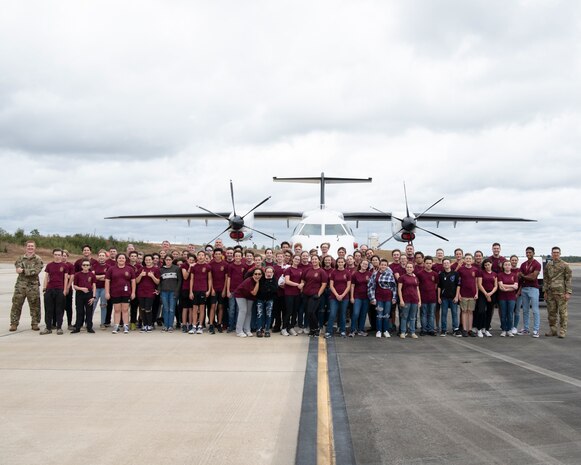 A group of cadets pose for a group photo in front of a C-146A Wolfhound aircraft.