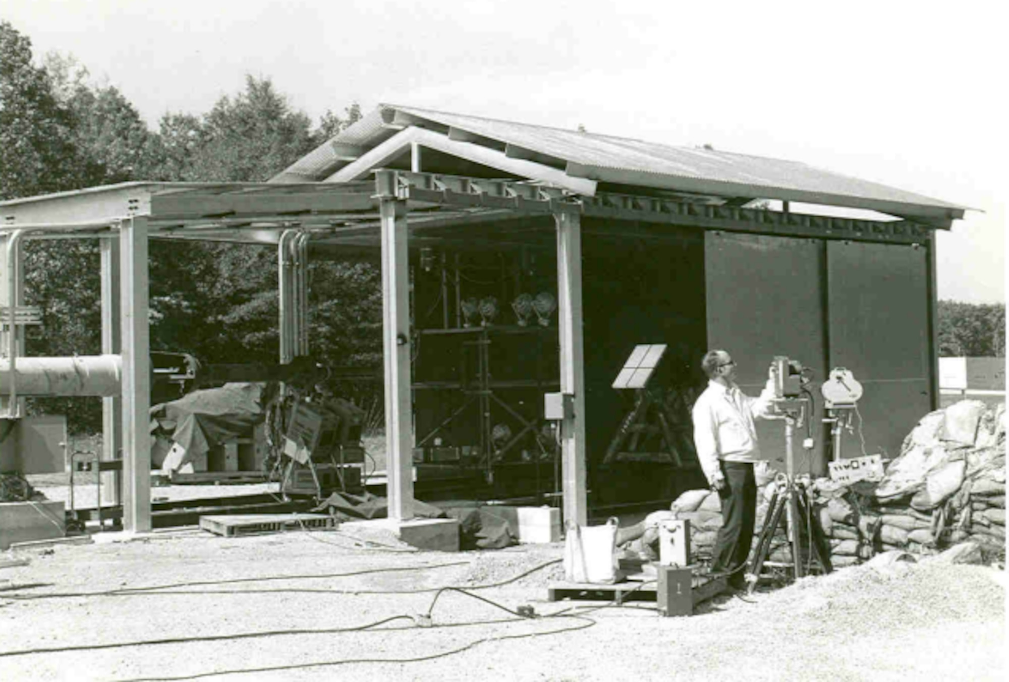 Herb Wiker makes final adjustments to the high-speed motion picture cameras set up at the Bird Impact Range at Arnold Air Force Base, Tennessee, in 1972. These cameras, operating at thousands of frames per second, captured the impacts of bird strikes simulated at the facility, more famously known as the “Chicken Gun.” Strikes were simulated by launching chicken carcasses at test articles, and the muzzle of the launcher can be seen beneath the steel structure on the left. The first shot from the Chicken Gun was fired 50 years ago. (U.S. Air Force photo)