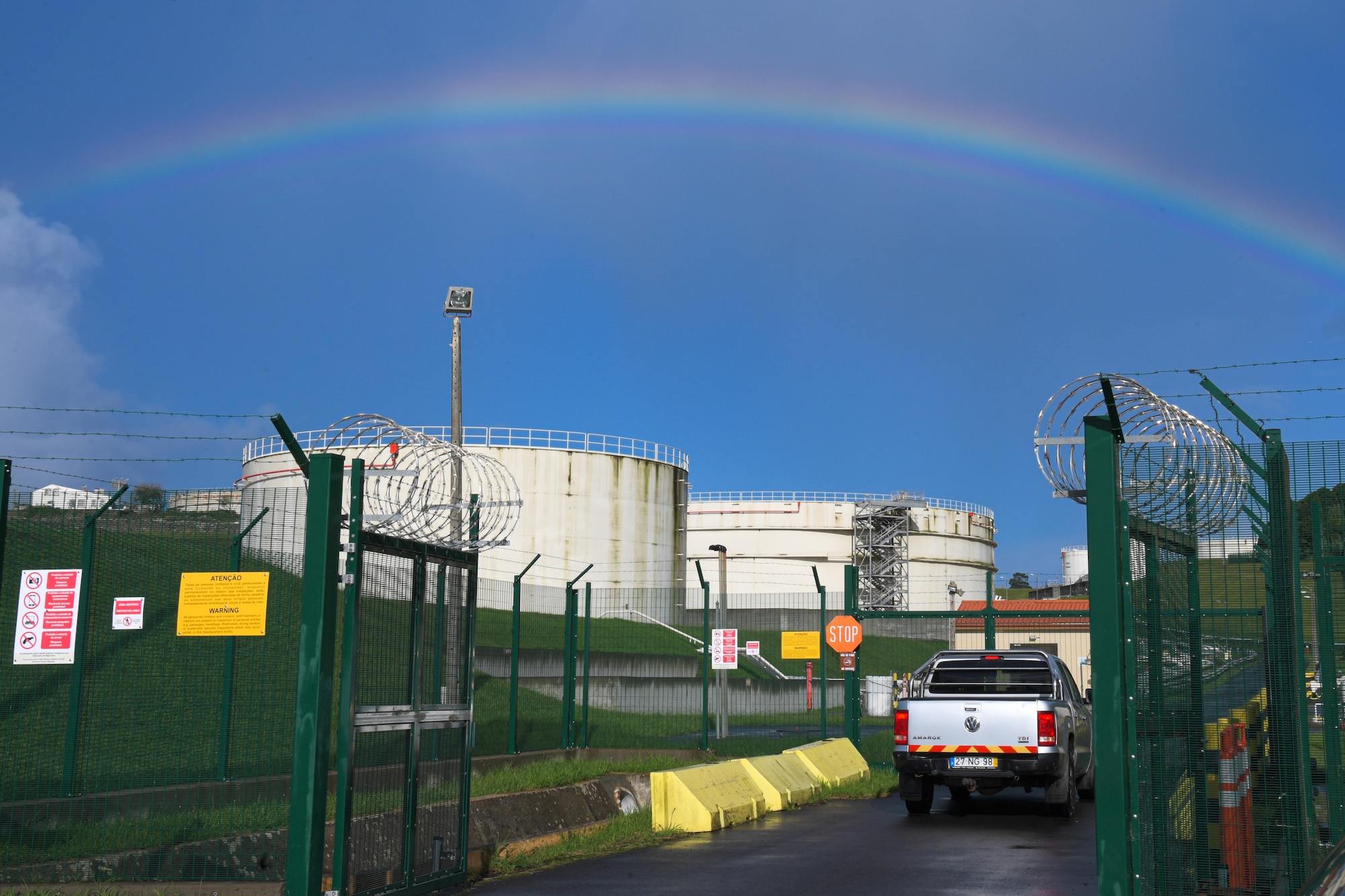 a rainbow is over fuel tanks with a blue sky