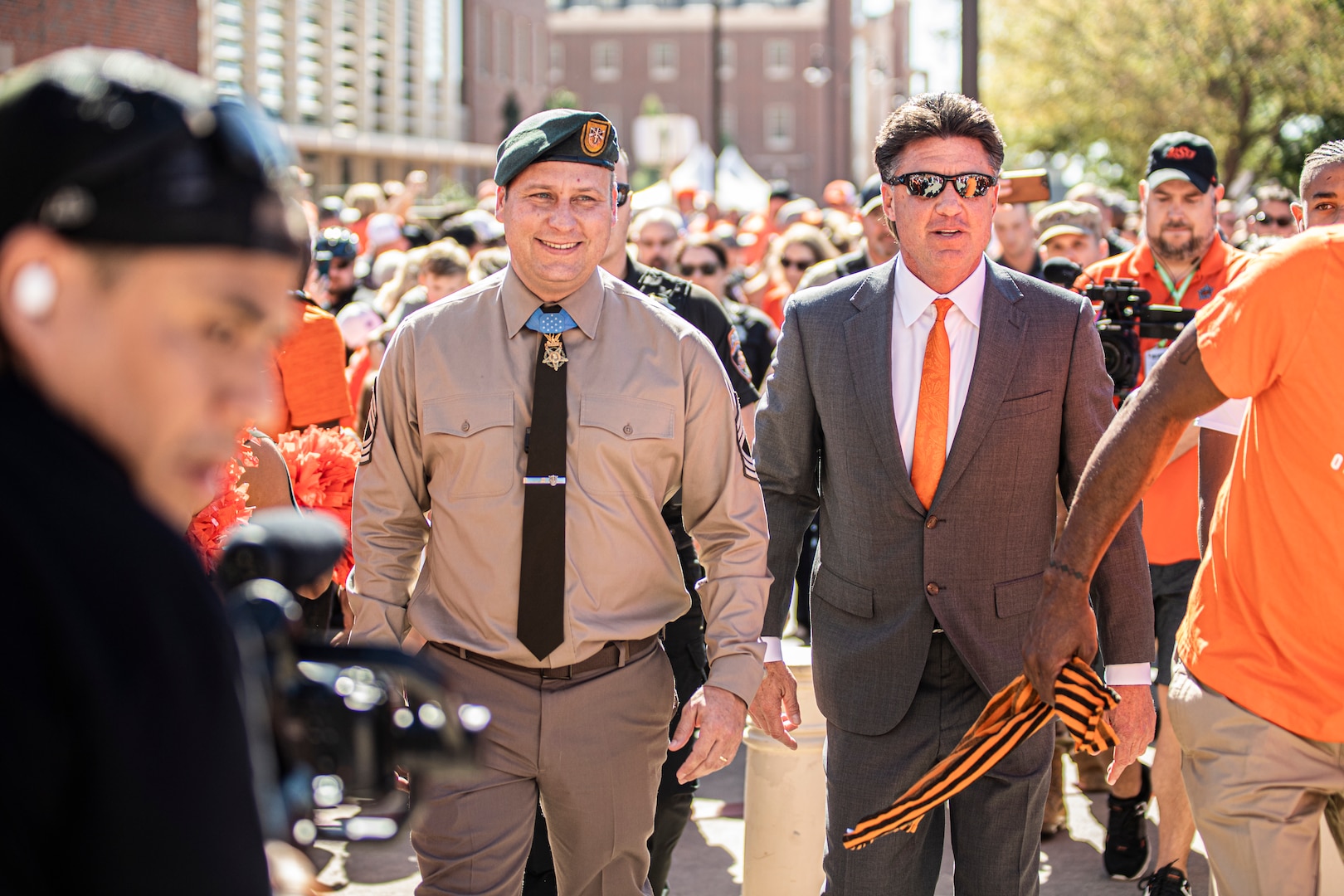 Master Sgt. Earl Plumlee, a Medal of Honor recipient and Oklahoma native, walks with Oklahoma State University head football coach Mike Gundy during The Walk, an Oklahoma State University tradition where members of the football team walk from the Student Union to Boone Pickens Stadium before games, in Stillwater, Oklahoma, Oct. 22, 2022. Plumlee attended the Oklahoma State University homecoming game and walked with head football coach Mike Gundy during The Walk. (Oklahoma National Guard photo by Sgt. Anthony Jones)