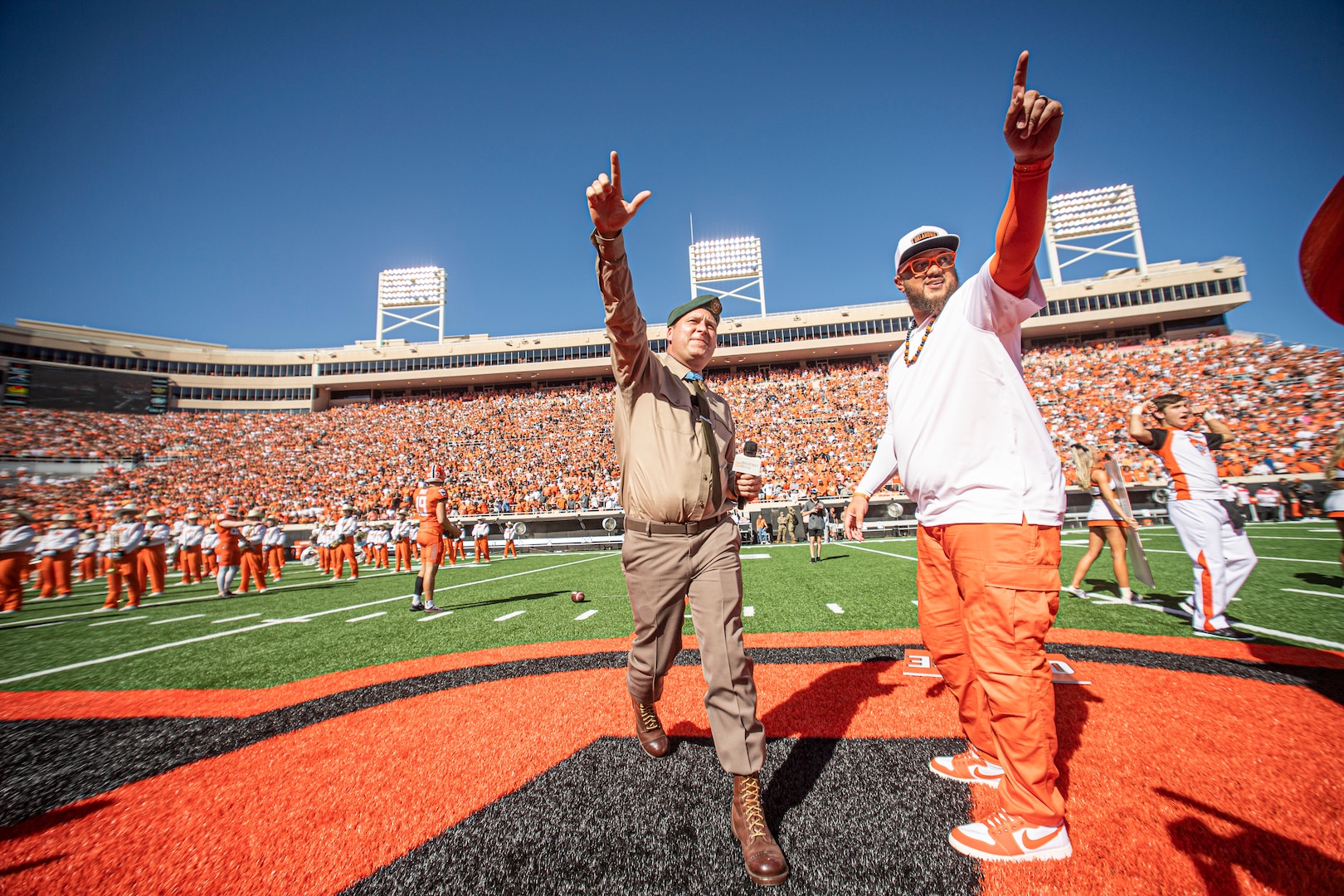 Master Sgt. Earl Plumlee, a Medal of Honor recipient, leads the Orange Power chant alongside Oklahoma State University's Les Thomas Sr. during pre-game activities at the Oklahoma State University homecoming football game in Stillwater, Oklahoma, Oct. 22. 2022. Plumlee, an Oklahoma native, toured his home state Oct. 18-22 and attended the Oklahoma State University homecoming game where he was recognized as the Orange Power VIP of the game. (Oklahoma National Guard photo by Sgt. Anthony Jones)