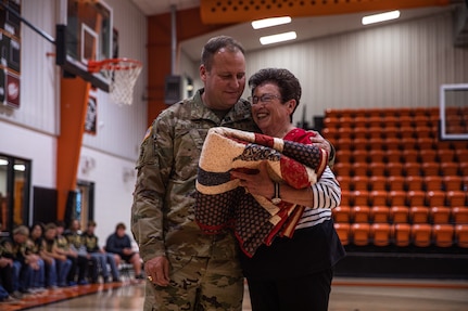 Master Sgt. Earl Plumlee, Medal of Honor recipient, receives a blanket from one of his former teachers at Merritt Public Schools in Merritt, Oklahoma, Oct. 21, 2022. Plumlee, a native Oklahoman, toured his home state Oct. 18-22. During his visit, Plumlee spoke at a Merritt High School football pep rally about his experiences being a Medal of Honor recipient and what it meant to be back home. (Oklahoma National Guard photo by Sgt. Reece Heck)