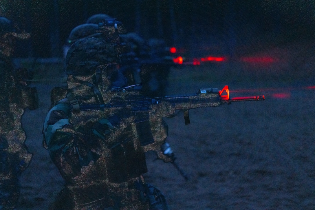 Marines fire their weapons at night.