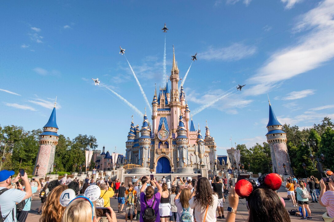 Aircraft fly over a castle as people watch.