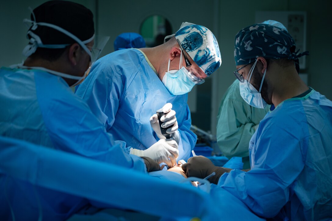 Three medical professionals perform surgery.