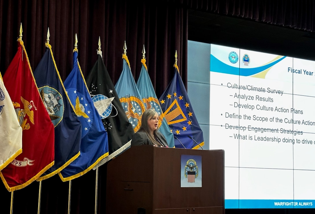 Female at podium presenting PowerPoint slide