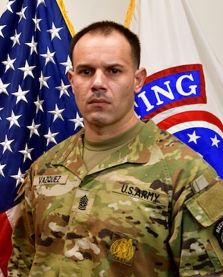 Soldier standing in front of two flags.
