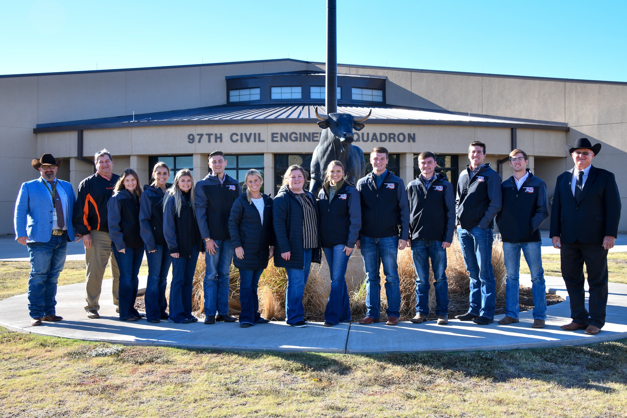 Oklahoma State University’s Agricultural Leadership Experience (OALE) students pose for a photo with Chuck Butchee (right), 97th Civil Engineer Squadron (CES) deputy squadron commander, and Dave Wallace (left), 97th CES installation chief, in front of the 97th CES at Altus Air Force Base, Oklahoma, Oct. 25, 2022. OALE students have visited Altus annually for over a decade. (U.S. Air Force photo by Airman 1st Class Kari Degraffenreed)