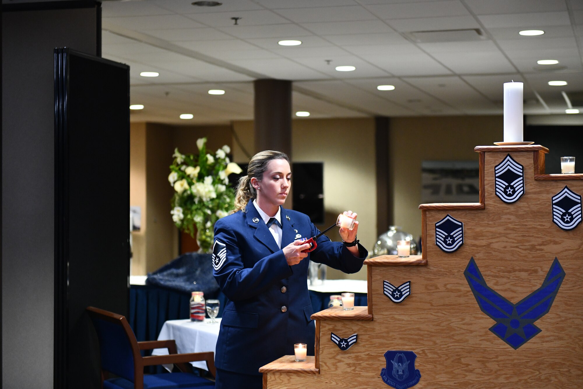 Master Sgt. Shelby Perkins, 910th Mission Support Group education and training manager, lights a candle representing the Air Force's master sergeants during a chief induction ceremony at Youngstown Air Reserve Station, Ohio, Oct. 15, 2022.