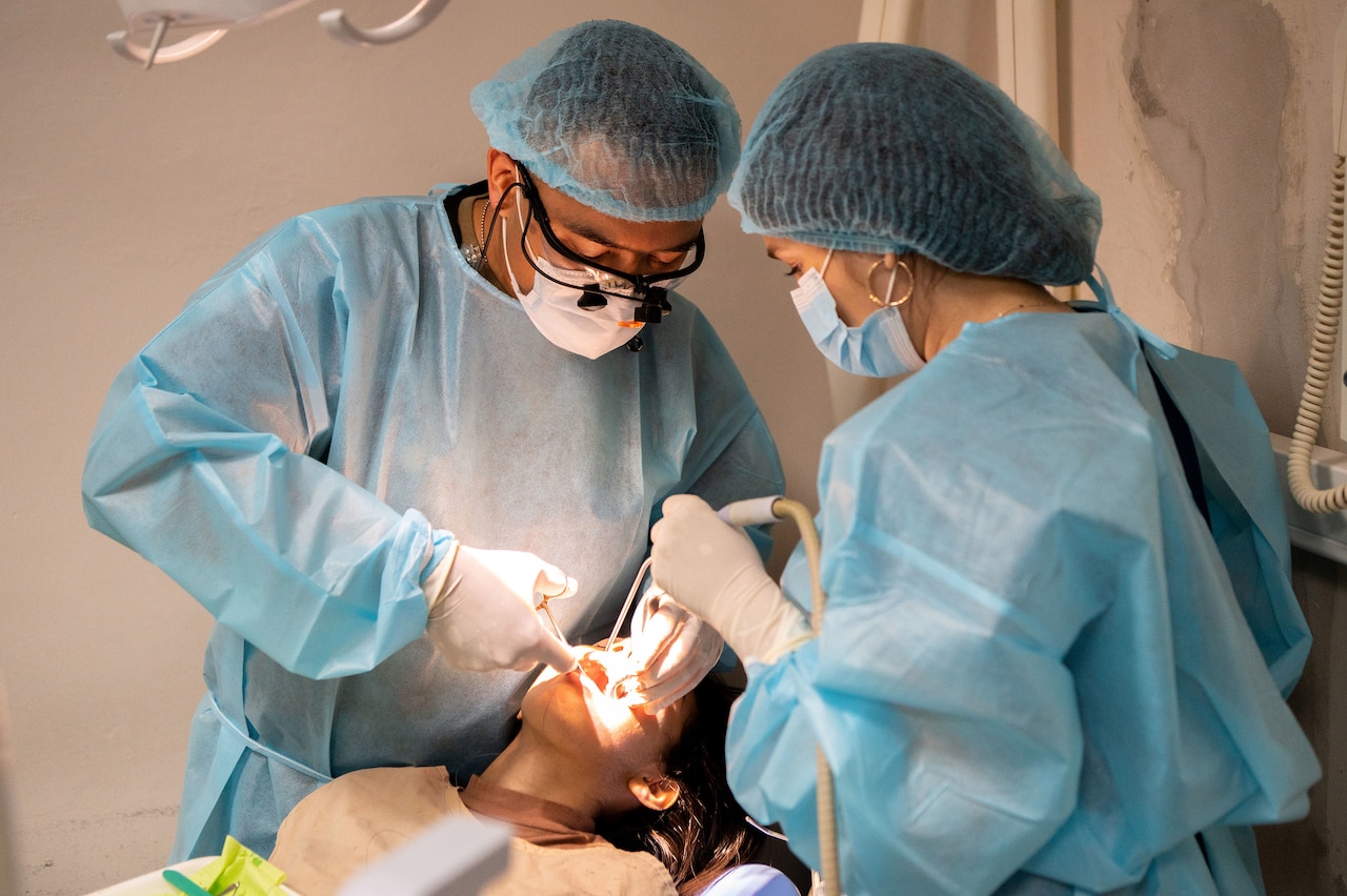 Two medical professionals work on a patient's mouth.