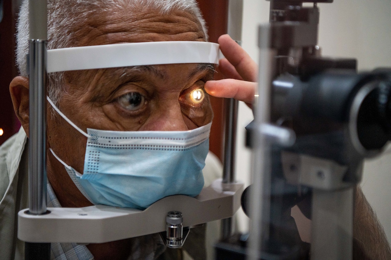 A light shines into the eye of a man during an eye exam.