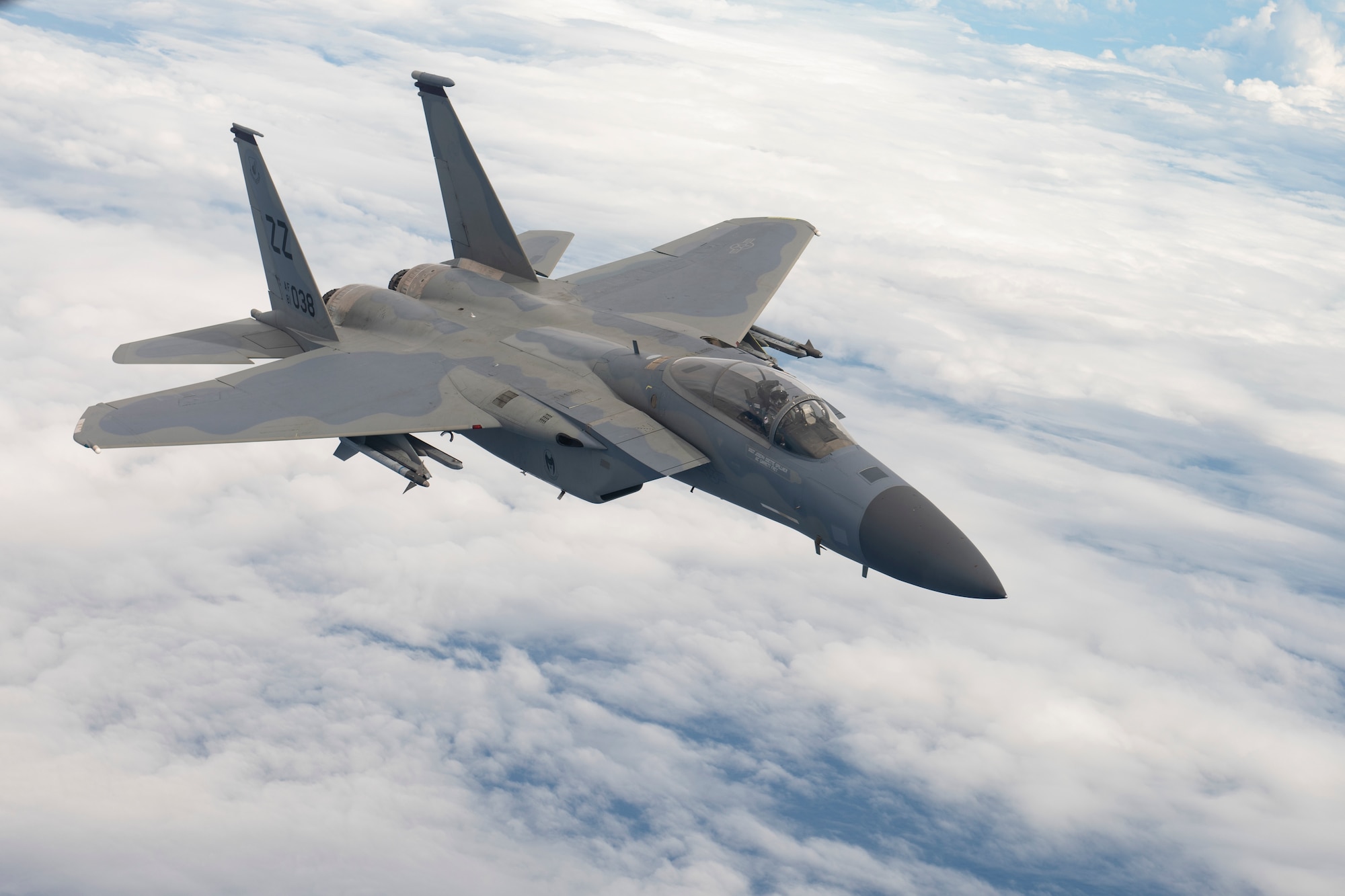 An aerial shot of an F-15 flying about some clouds.