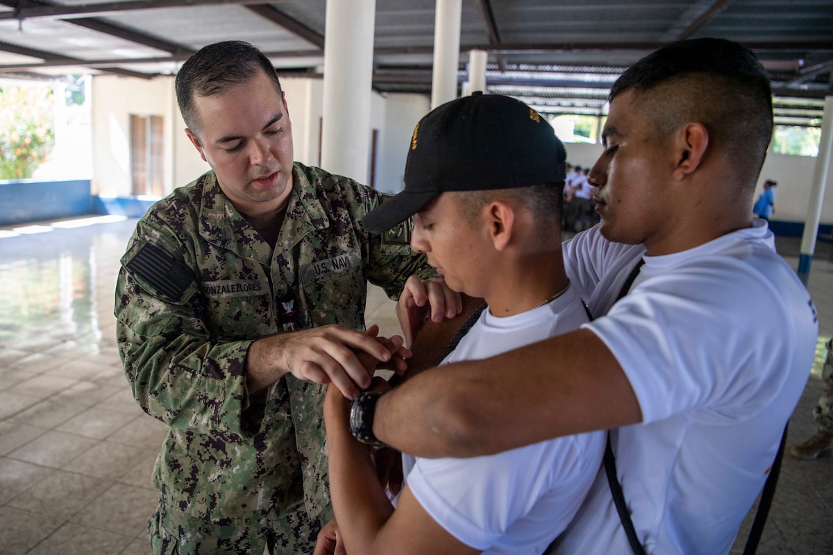 Hospital Corpsman 3rd Class Sebastian Gonzalez-Lores, left, from New Braunfels, Texas, attached to the Military Sealift Command hospital ship USNS Comfort (T-AH 20), teaches tactical carrying techniques to Guatemalan service members during a tactical combat casualty care subject matter expert exchange in Puerto Barrios, Guatemala, Oct. 27, 2022.