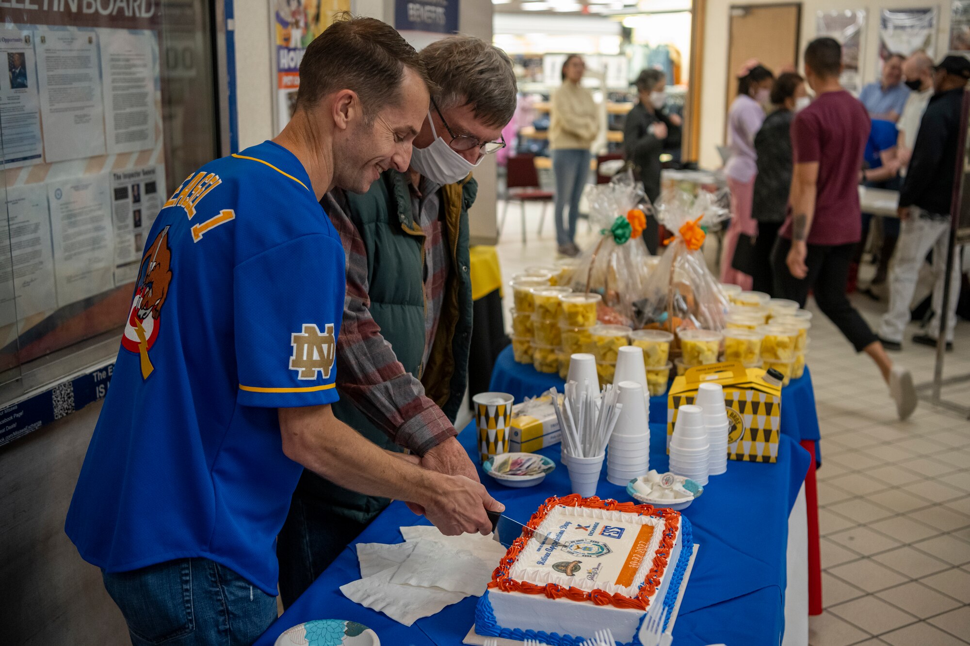 Two people cut cake together white, red, and blue cake together.