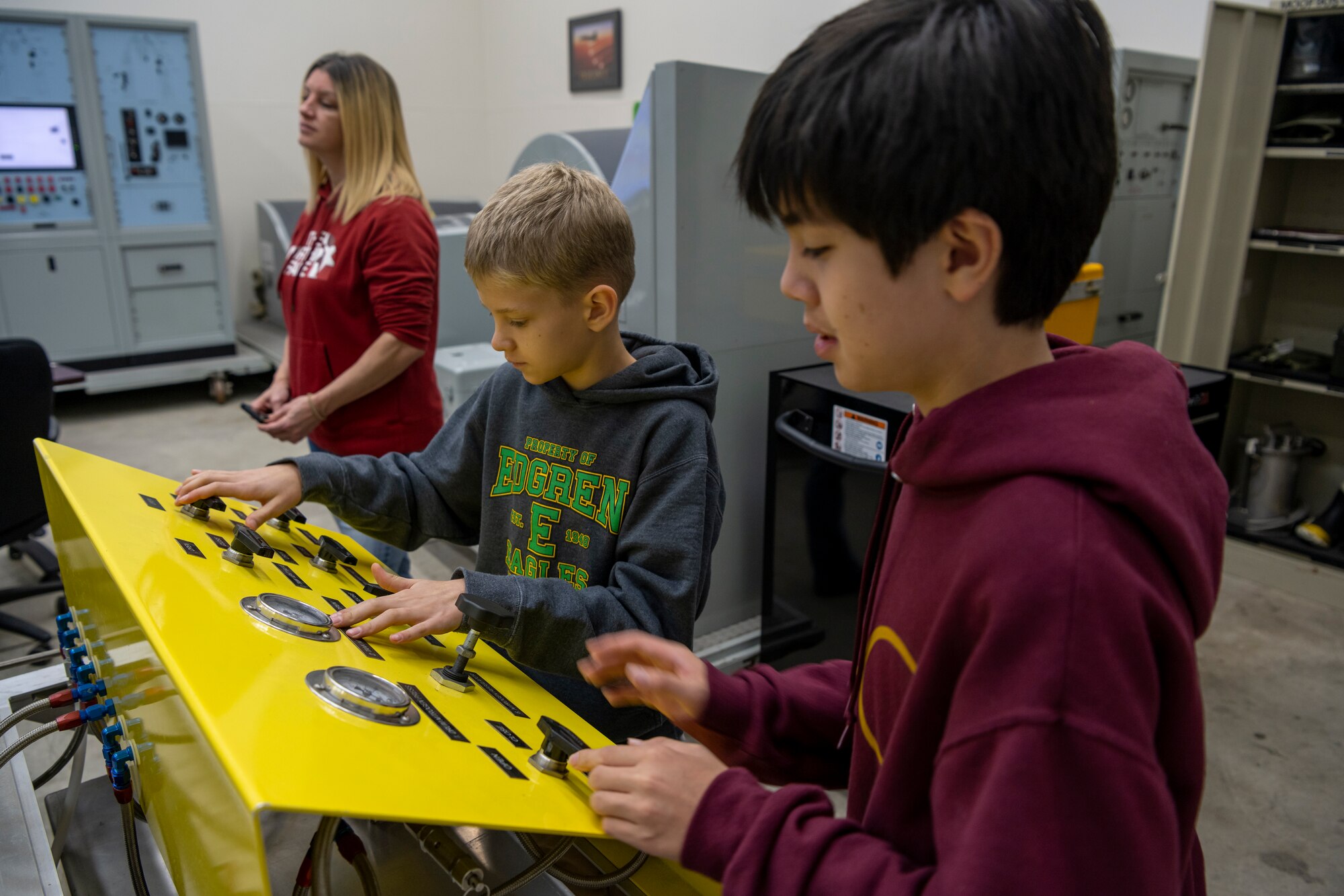 Students playing with knobs on yellow board.