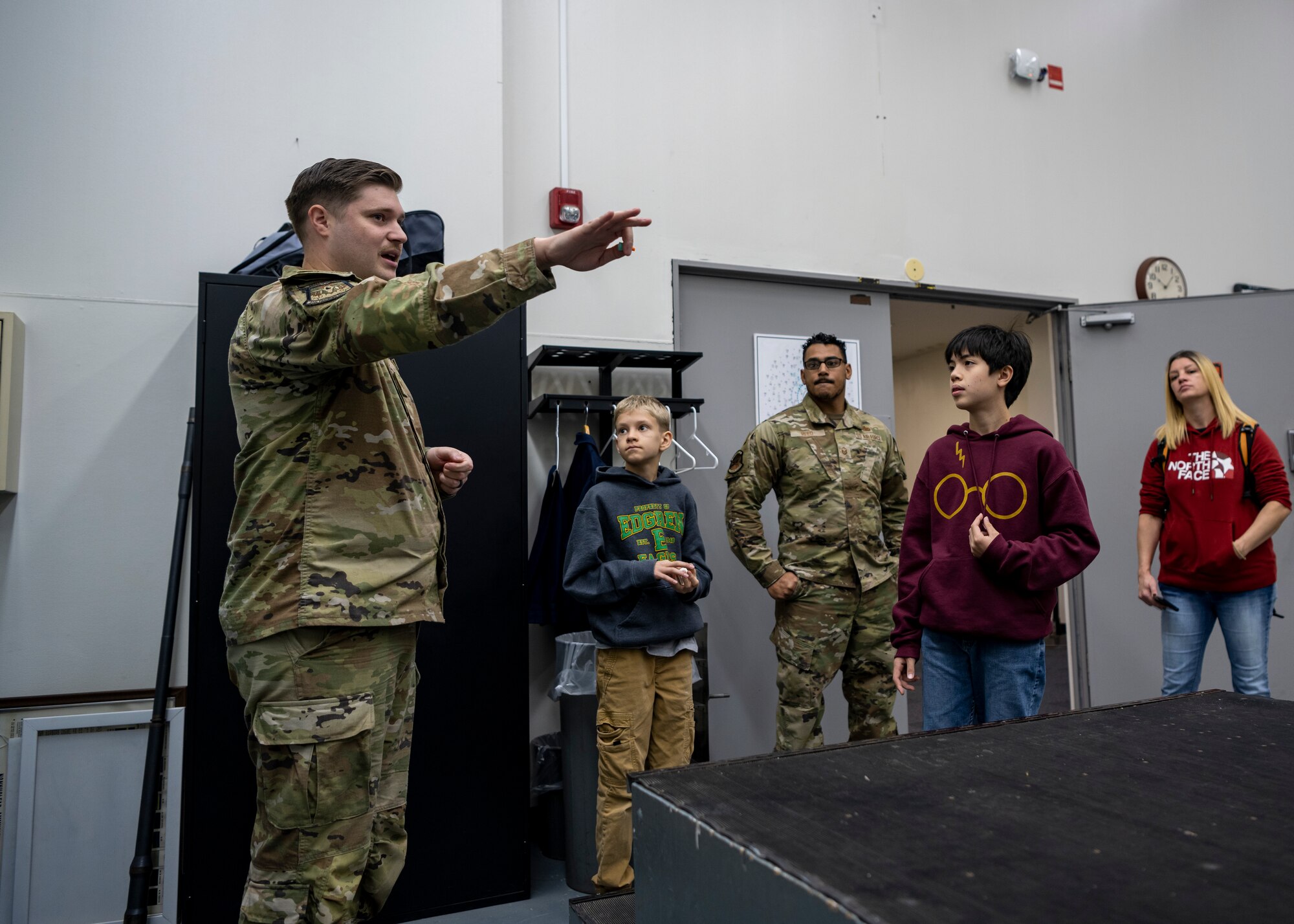 Airman points at an fighter jet gun mount and explains what the weapons systems do.
