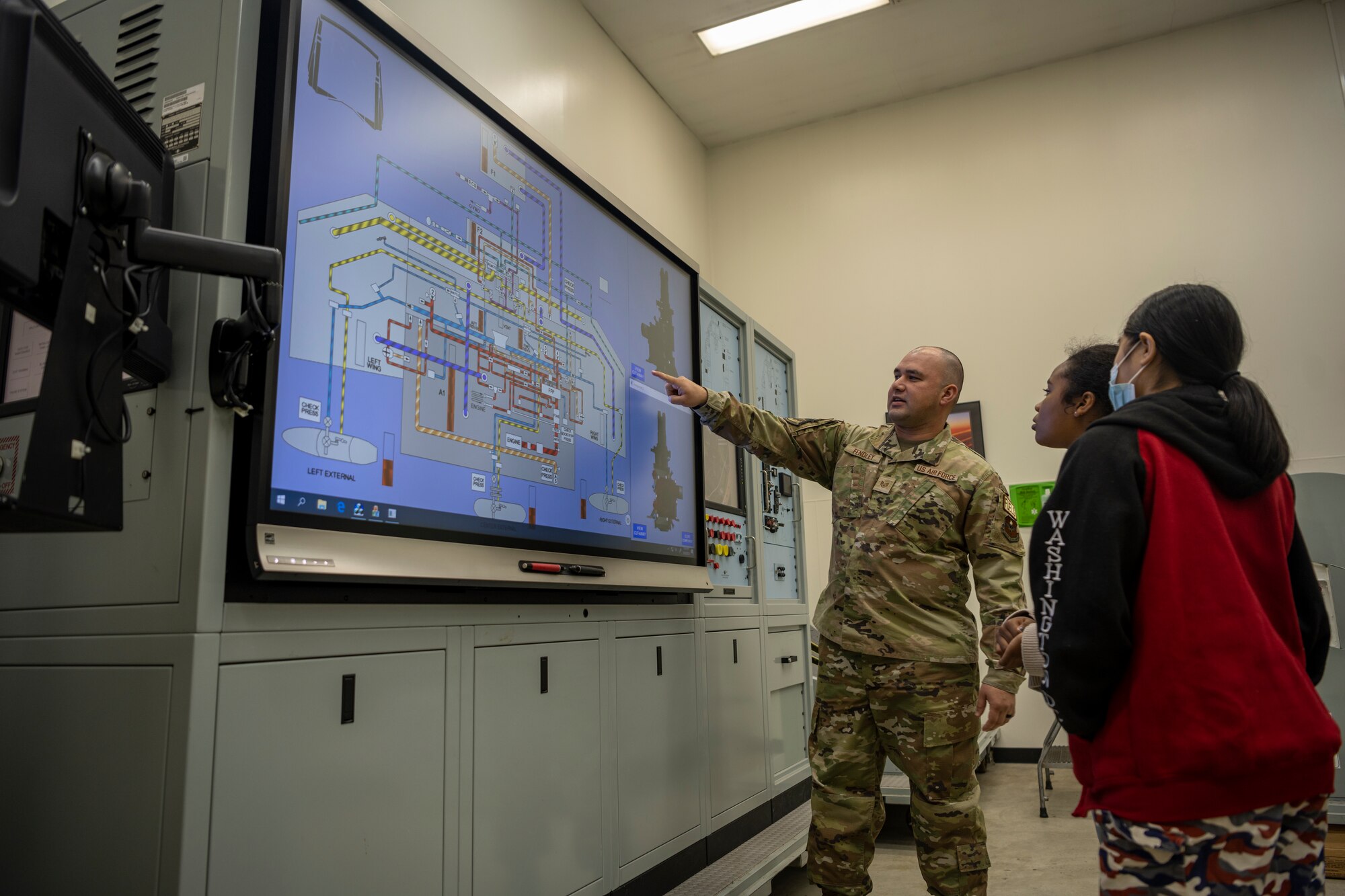 Instructor points at interactive screen showing how the fuel systems runs throughout the fighter jet.