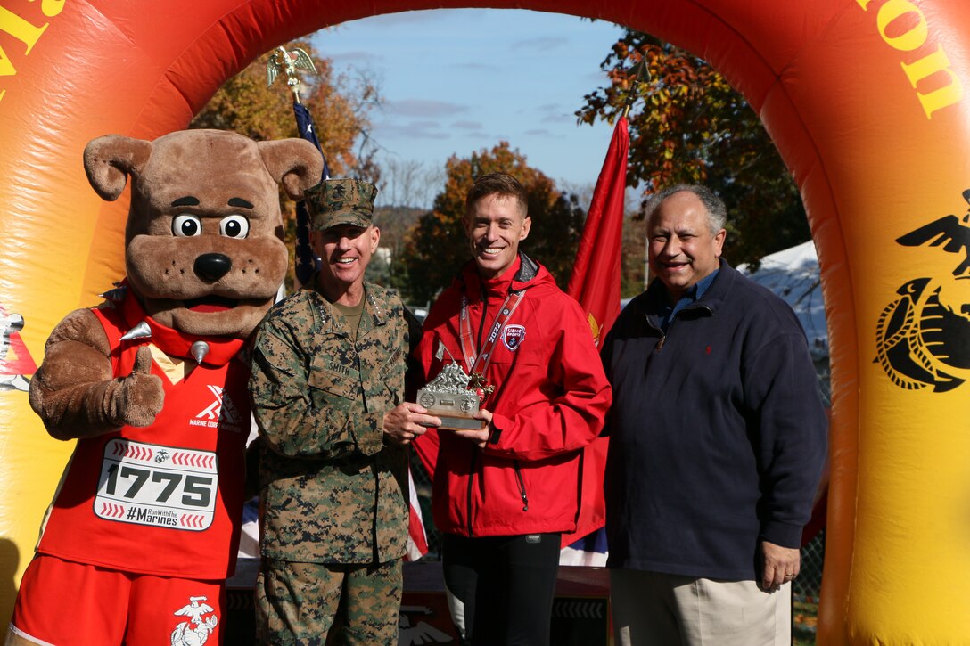 Marine Corps Capt Kyle King of Twentynine Palms, California celebrates his victory of the 47th Marine Corps Marathon as well as the Armed Forces Men's Gold with the Secretary of the Navy Honorable Carlos Del Toro (right) and the Assistant Commandant of the Marine Corps General Eric Smith (left)...and of course the MCM mascot Miles.  The 2022 Armed Forces Marathon Championship held in conjunction with the 47th Marine Corps Marathon in Washington, D.C.  The Armed Forces Championship features teams from the Marine Corps, Navy (with Coast Guard runners), and Air Force.  Department of Defense Photo by Mr. Steven Dinote - Released.