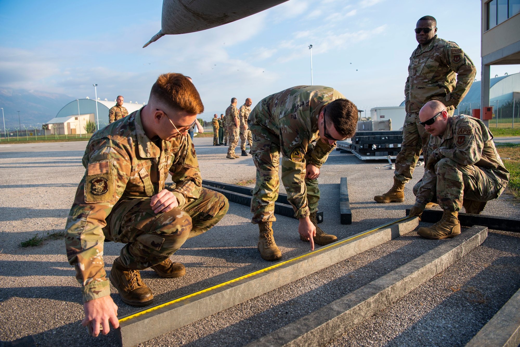 U.S. Airmen set up dunnage for a bag lift during a crashed, damaged or disabled aircraft recovery training at Aviano Air Base, Italy, Oct. 20, 2022. The dunnage is a set of wooden beams that was inserted under the bags that were inflated to lift the jet, helping the bags keep shape during the lift. (U.S. Air Force photo by Airman 1st Class Thomas Calopedis)