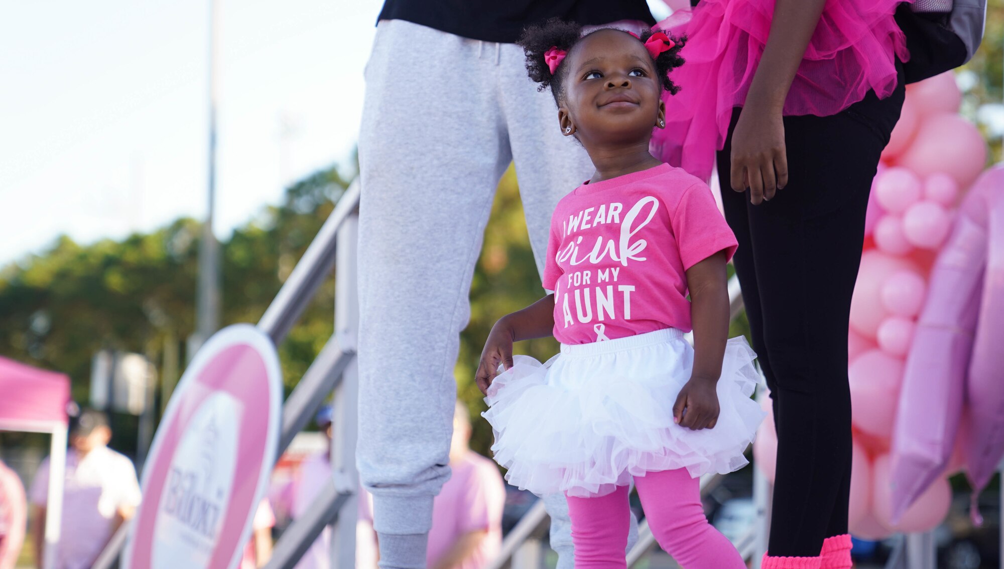 Brooklyn Davis, niece of U.S. Air Force Tech. Sgt. LeVonya Davis, 81st Medical Support Squadron medical information systems section chief,  watches her aunt give a speech at the Mississippi Gulf Coast Strides Against Breast Cancer 5K in held at the AJ Holloway Sports Complex in Biloxi, Mississippi, Oct. 15, 2022.