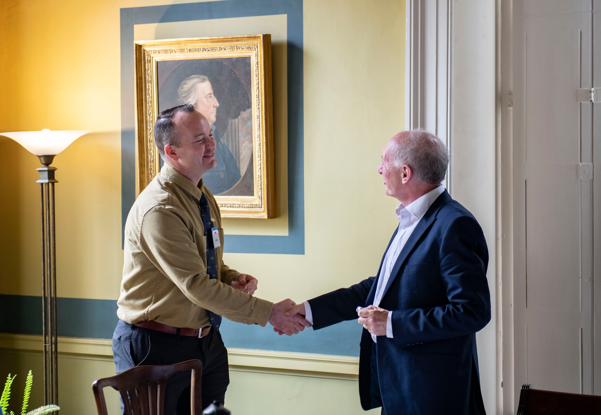 Lt. Col. Jason Barker, 48th Fighter Wing chaplain, left, presents a military challenge coin to Alan Bookbinder, Downing College master, as a thank you for hosting members of the Leadership Connect Program, at Downing College