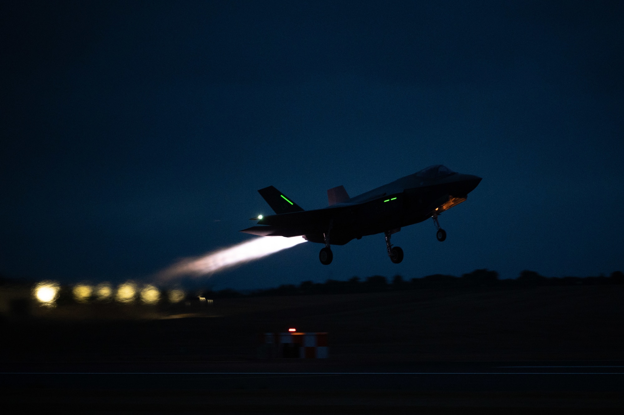 Photo of a fighter jet taking off at night using its afterburner.