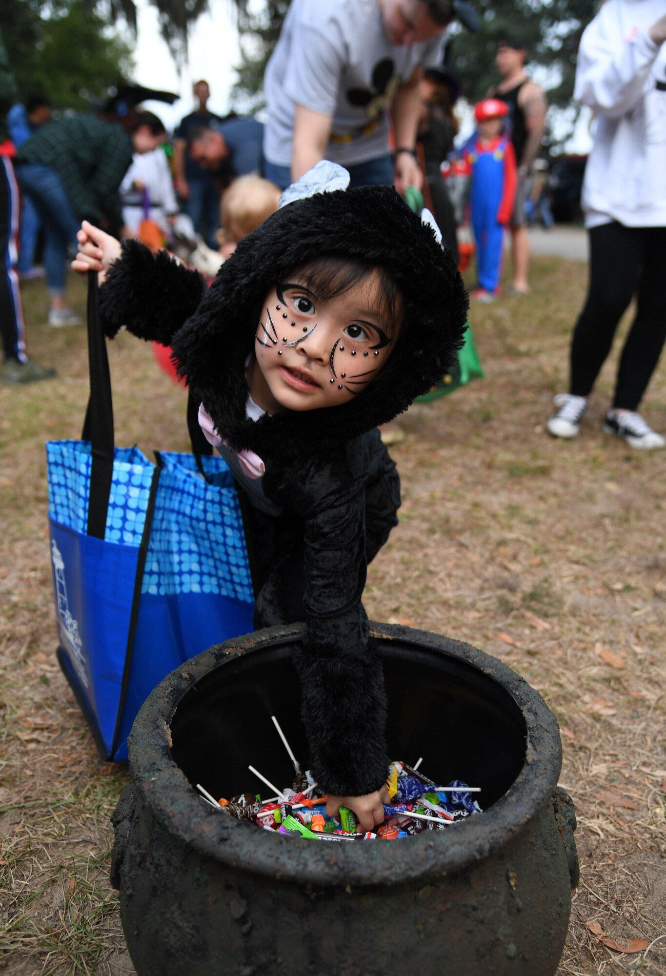 Manami Tsang, daughter of U.S. Air Force Tech. Sgt. Richard Tsang, 338th Training Squadron instructor, collects candy during Ghouls in the Park at the marina park at Keesler Air Force Base, Mississippi, Oct. 28, 2022.