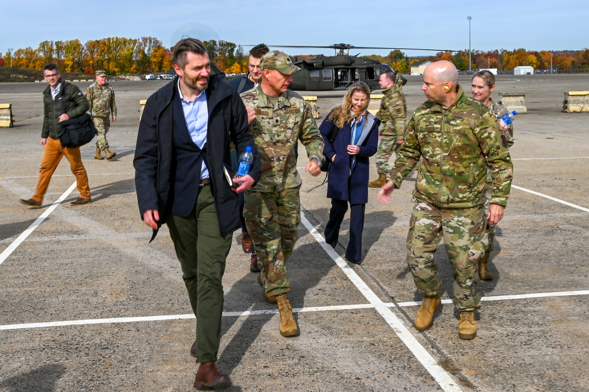 Civilians and Air Force personnel walk away from a helicopter.