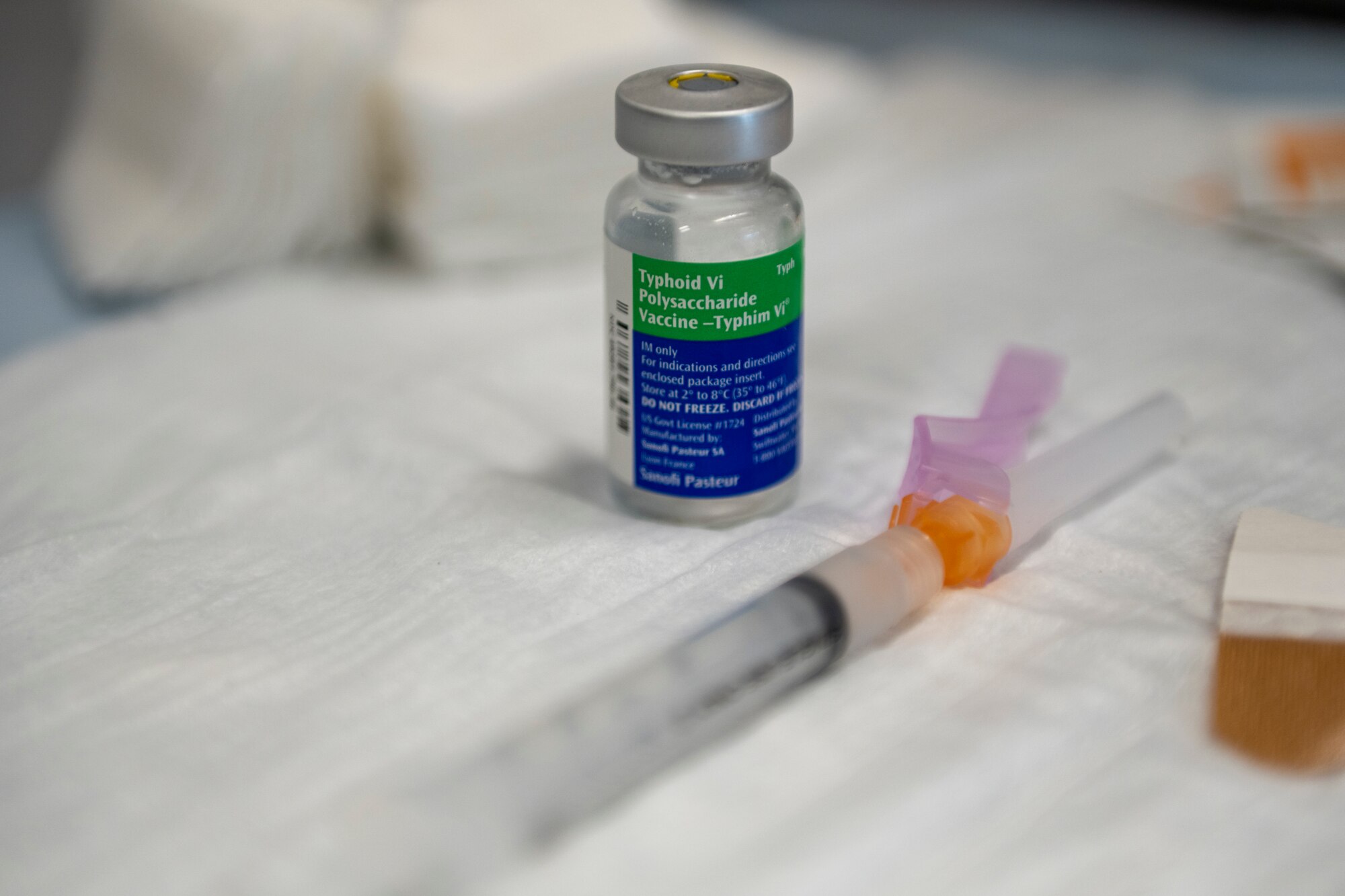 A vial of Typhoid vaccine and a syringe sit on a table