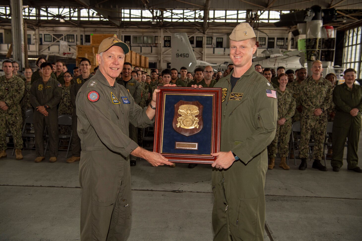 Vice Adm. Kenneth Whitesell, Commander, U.S. Naval Air Forces, left, presents the 2021 Chief of Naval Operations (CNO) Aviation Safety Award to Cmdr. Jeremy Bartowitz, commanding officer of the “Titans” of Fleet Multi-Mission Squadron (VRM) 30, and his squadron during an award ceremony held aboard Naval Air Station North Island, Oct. 20, 2022.