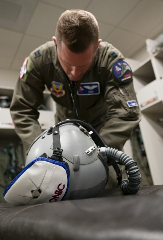 Capt. Tom, 94th Fighter Squadron pilot, prepares his helmet for scrambling to his aircraft during the Battle of Britain Commemoration held by the 94th FS, Joint Base Langley-Eustis, Virginia, Oct. 21, 2022. Pilots were assigned call signs unique to the time period and were provided accurate displays of the British coast in their cockpits to reflect the airspace they would be defending during the simulated event. (U.S. Air Force photo by Tech. Sgt. Matthew Coleman-Foster)