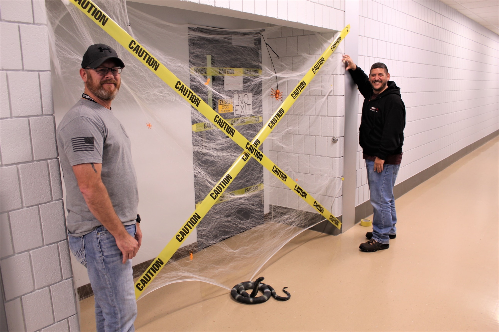 Two men stand outside an office door marked off with caution tape