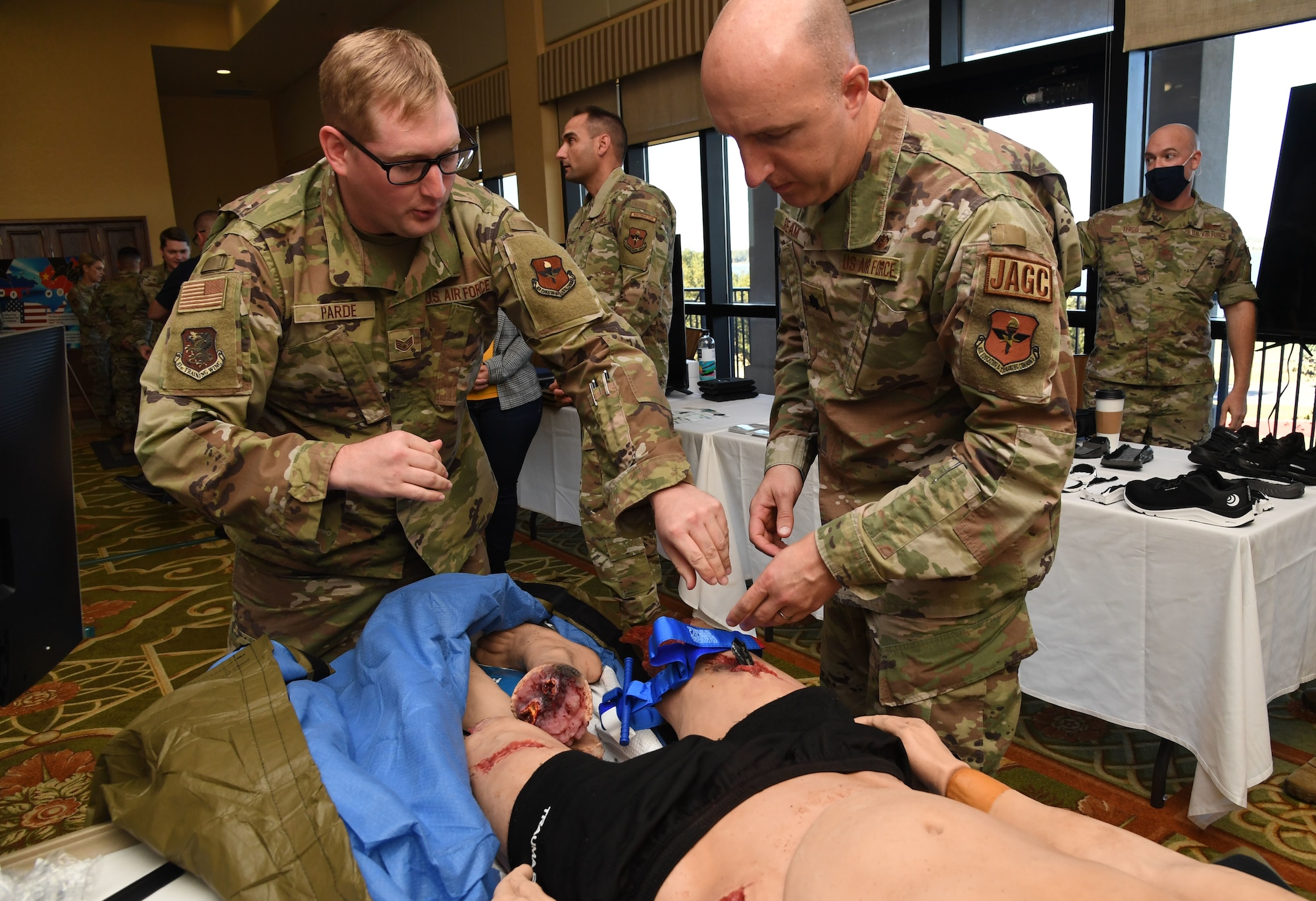 U.S. Air Force Staff Sgt. Timothy Parde, 81st Medical Support Squadron tactical combat casualty care advisor, demonstrates tourniquet application with Lt. Col. Matt Ream, 82nd Training Wing staff judge advocate, during the innovation expo during the Second Air Force Technical Training-101 Seminar inside the Bay Breeze Event Center at Keesler Air Force Base, Mississippi, Oct. 26, 2022.