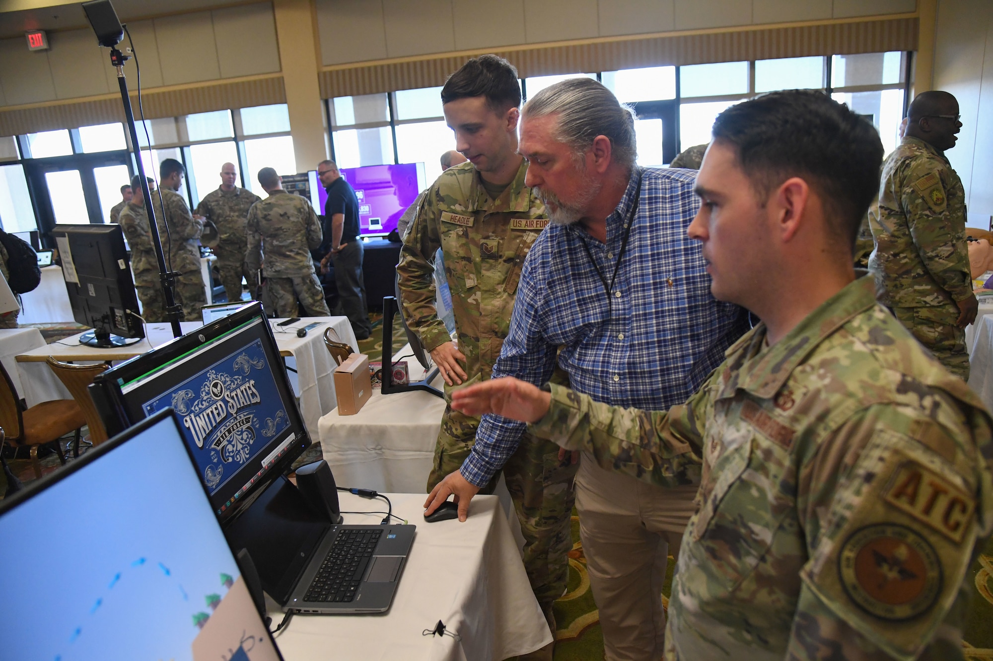 U.S. Air Force Staff Sgt. Zachary Headlee, 81st Training Support Squadron interactive multimedia developer, Ronald Warr, 81st TRSS information technology specialist, and Tech. Sgt. Jeremy Roosa, 334th Training Squadron instructor, discuss the instructional technology unit capabilities and products during the innovation expo during the Second Air Force Technical Training-101 Seminar inside the Bay Breeze Event Center at Keesler Air Force Base, Mississippi, Oct. 26, 2022.