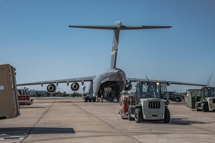 a C-17 Globemaster III is refueled on an airfield while receiving cargo