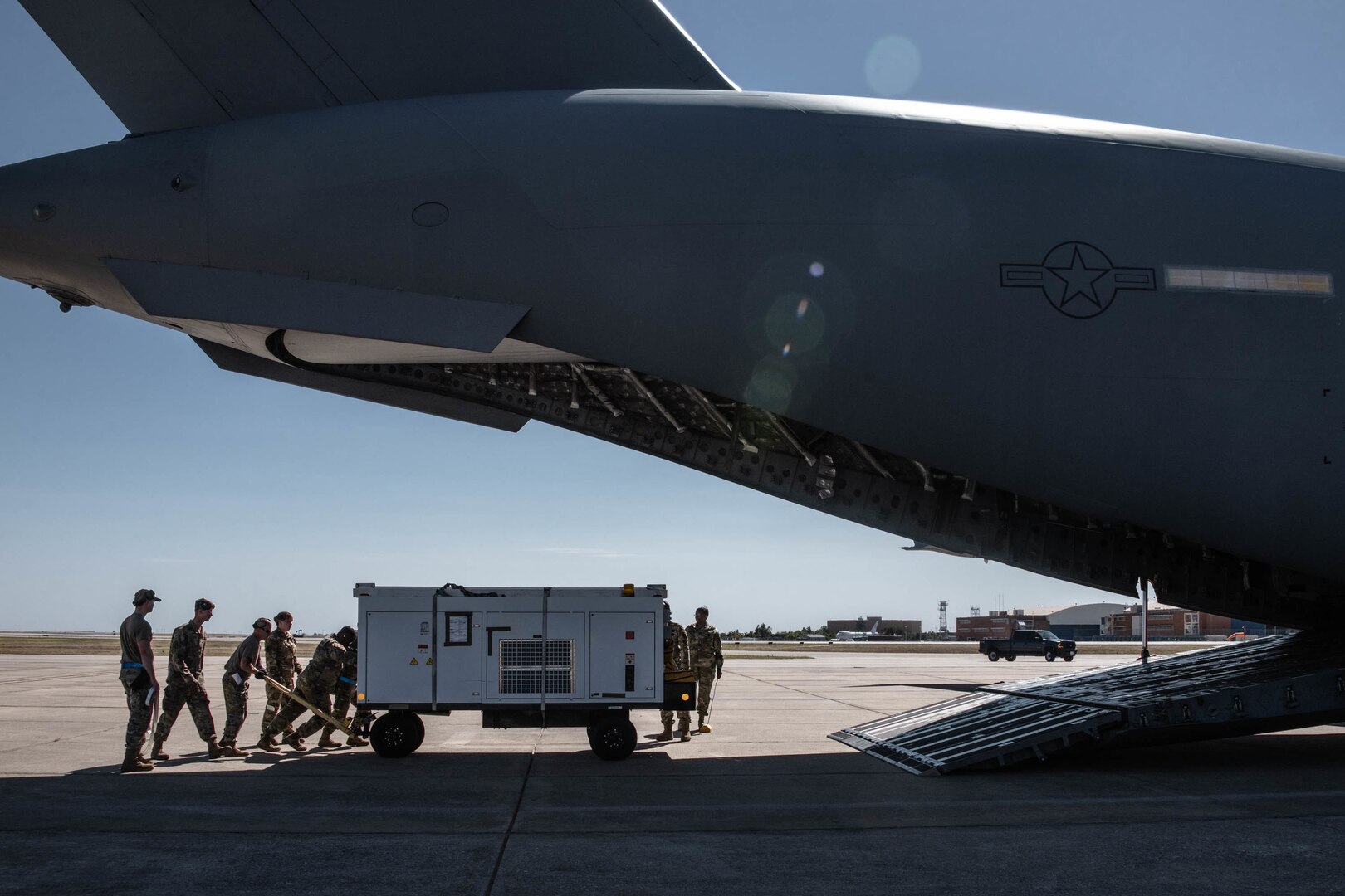 people load a wheeled cart onto a C-17 Globemaster III