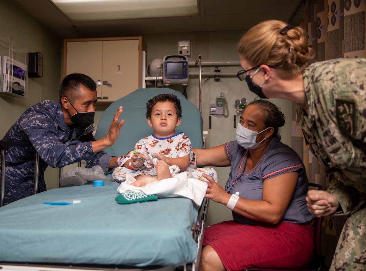 Capt. Kathryn Elliott, commanding officer of Medical Treatment Facility aboard the Military Sealift Command hospital ship USNS Comfort (T-AH 20), right, checks on a young patient aboard Comfort.