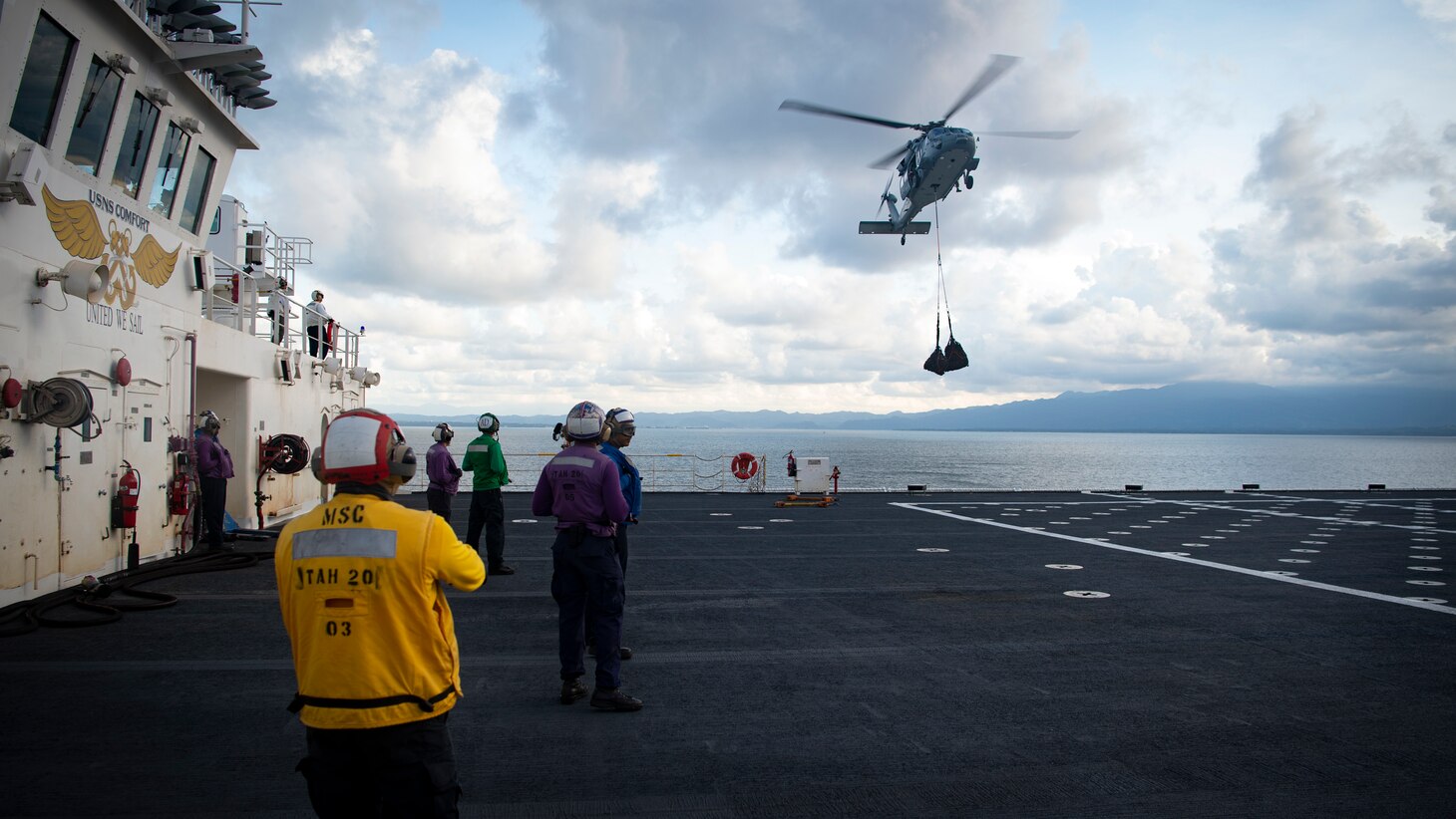 221026-N-MY642-1007 PUERTO BARRIOS, Guatemala (Oct. 26, 2022) An MH-60S Seahawk, assigned to the "Chargers" of Helicopter Sea Combat Squadron 26, carries cargo nets from the coast of Puerto Barrios after the hospital ship USNS Comfort's (T-AH 20) arrival, Oct. 26, 2022. Comfort is deployed to U.S. 4th Fleet in support of Continuing Promise 2022, a humanitarian assistance and goodwill mission conducting direct medical care, expeditionary veterinary care, and subject matter expert exchanges with five partner nations in the Caribbean, Central and South America. (U.S. Navy photo by Mass Communication Specialist 1st Class Donald R. White Jr.)