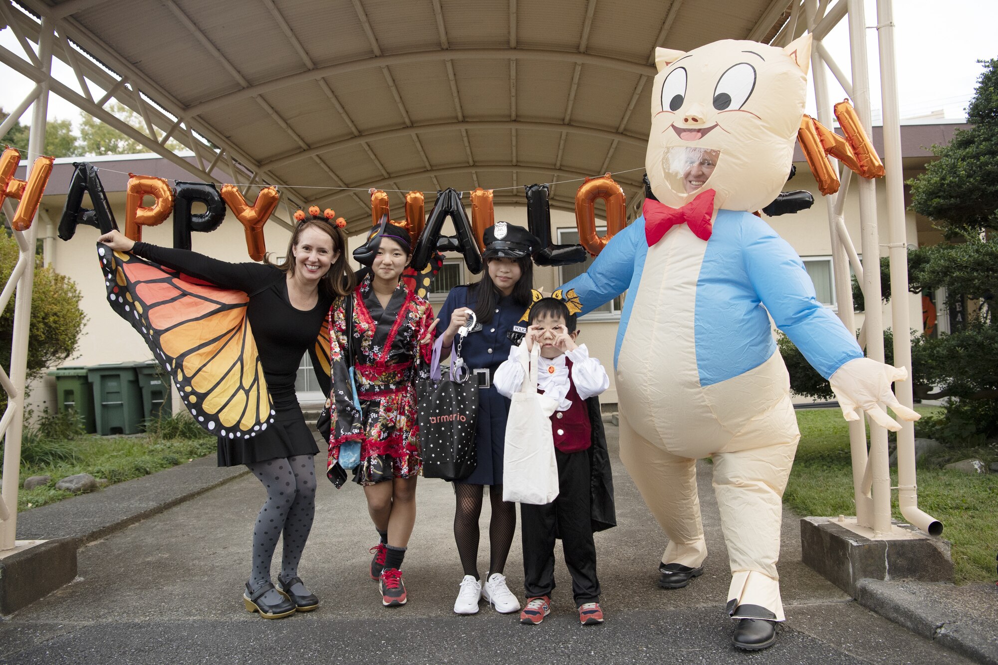 Jennifer Rhyne, Fujimi Elementary School alternate contract English teacher, left, poses for a photo with her students Rin Imai, center left,  and Kao Nishibe, center, alongside Hayato Morizono, center right, and Col. Craig Rhyne, 374th Dental Squadron commander, during trick-or-treating at Yokota Air Base, Japan, Oct. 29, 2022. This year, members of the base were able to sponsor up to ten visitors onto base for trick-or-treating. Activities like trick-or-treating help build mutual understanding of the distinctive cultures of the U.S. and Japan, deepen friendships, and further strengthen the critical relationship Yokota has with its surrounding communities. (U.S. Air Force photo by Tech. Sgt. Christopher Hubenthal)