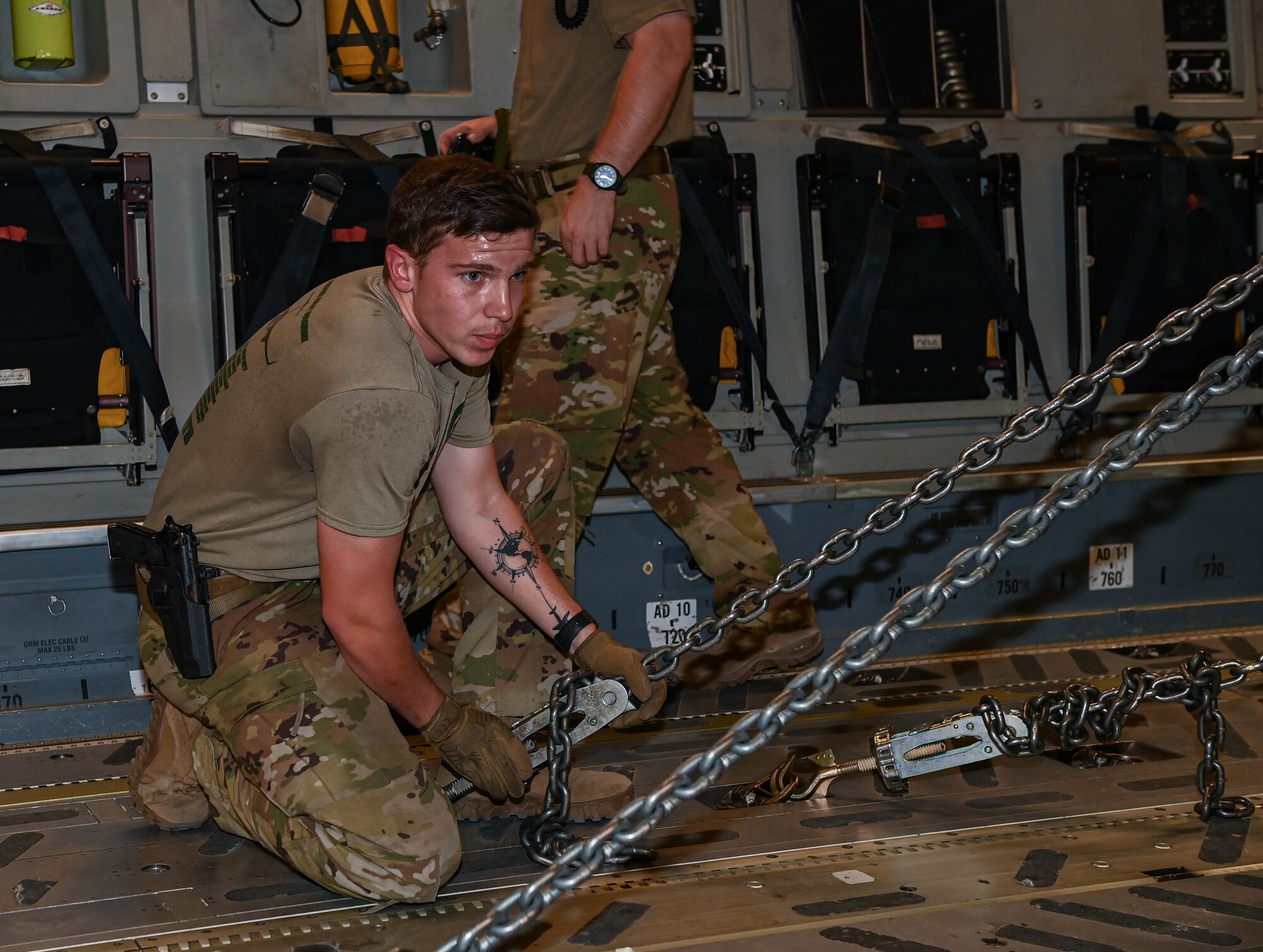 U.S. Air Force Senior Airman Ryan Alix, an 816th Expeditionary Airlift Squadron loadmaster, straps down a chain used to secure an M-1/A2 Abrams main battle Aug 27, 2022 at Ali Al Salem Air Base, Kuwait. Loadmasters ensure that cargo is properly balanced and secured before flight to ensure safe transportation. (U.S. Air National Guard photo by Master Sgt. Michael J. Kelly)
