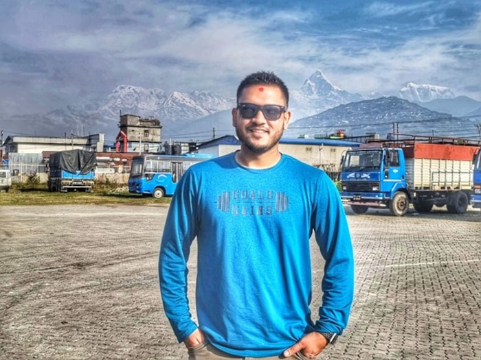 Airman in civilian clothing standing at a loading dock in front of mountains in Nepal