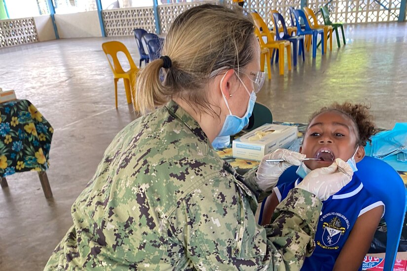 A sailor examines a child's mouth.