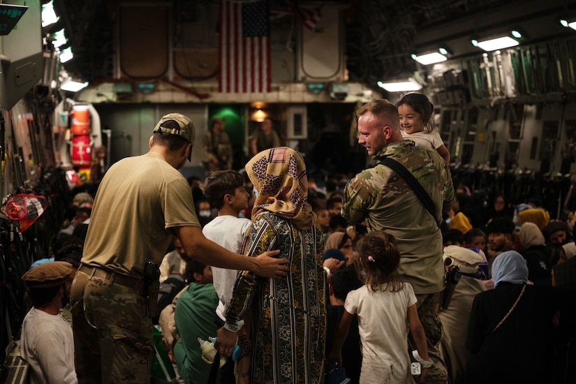 Airmen assists Afghan citizens aboard an aircraft.