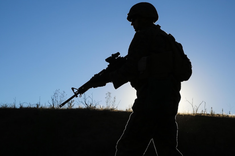A service member carries a rifle.